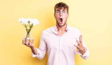 Genç ve yakışıklı bir adam şok olmuş ve şaşırmış hissediyor. çiçek konsepti