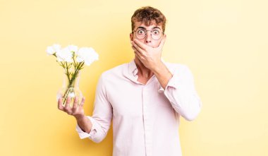 Genç ve yakışıklı bir adam elleri ile ağzını kapatıyor ve şok geçiriyor. çiçek konsepti