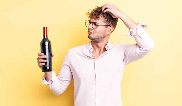 Jovem Homem Bonito Sentindo Intrigado Confuso Coçando Cabeça Garrafa Vinho — Fotografia de Stock