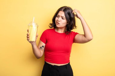 Genç, güzel bir kadın kafası karışmış, kafası karışmış, kaşınıyor. Milkshake konsepti