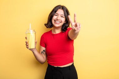 Gülümseyen ve mutlu görünen genç, güzel bir kadın zafer ya da huzur simgesi. Milkshake konsepti