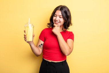 Genç ve güzel bir kadın, mutlu ve kendinden emin bir ifadeyle gülümsüyor, elleri çenesinde. Milkshake konsepti