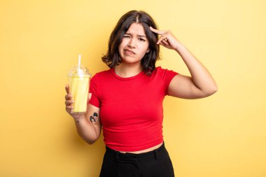 Genç ve güzel bir kadın kafası karışık ve şaşkın hissediyor, deli olduğunu gösteriyor. Milkshake konsepti