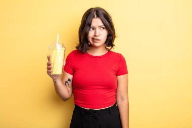 Genç, güzel bir kadın üzgün, üzgün ya da kızgın hissediyor ve yan tarafa bakıyor. Milkshake konsepti