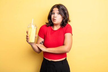 Genç, güzel bir kadın omuz silkiyor, kafası karışık ve kararsız. Milkshake konsepti