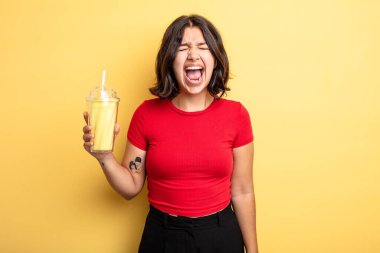 Genç ve güzel bir kadın agresif bir şekilde bağırıyor, çok kızgın görünüyor. Milkshake konsepti