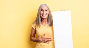 Orta yaşlı güzel bir kadın komik bir şakaya yüksek sesle gülüyor. boş tuval kavramı