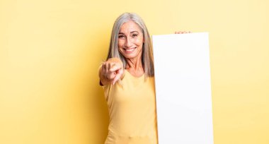 Orta yaşlı, güzel bir kadın kamerayı işaret ederek seni seçiyor. boş tuval kavramı