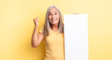 Orta yaşlı, güzel bir kadın şokta, gülüyor ve başarıyı kutluyor. boş tuval kavramı