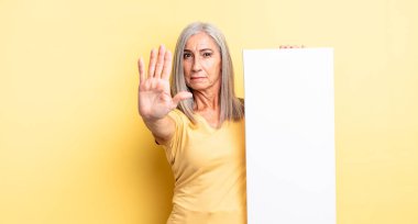 Orta yaşlı, güzel bir kadın ciddi görünüyor. Avuç içini gösteriyor. Durdurma hareketi yapıyor. boş tuval kavramı