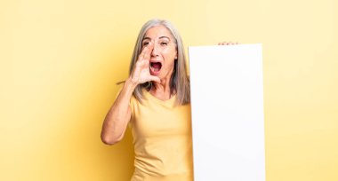 Orta yaşlı, güzel bir kadın kendini mutlu hissediyor. Elleri ağzının kenarında bağırıyor. boş tuval kavramı