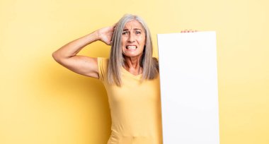 Orta yaşlı, güzel bir kadın stresli, endişeli ya da korkmuş, elleri başının üstünde. boş tuval kavramı