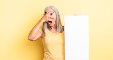 Orta yaşlı, güzel bir kadın şok olmuş, korkmuş ya da korkmuş görünüyor, yüzünü elleriyle kapatıyor. boş tuval kavramı