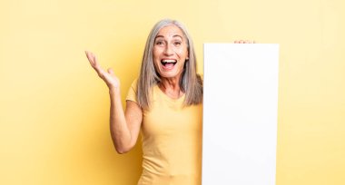 Orta yaşlı, güzel bir kadın inanılmaz bir şey karşısında mutlu ve şaşkın hissediyor. boş tuval kavramı