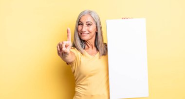 Orta yaşlı, güzel bir kadın gururla gülümsüyor ve kendinden emin bir numara oluyor. boş tuval kavramı