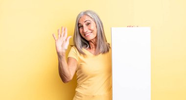 Orta yaşlı, güzel bir kadın mutlu bir şekilde gülümsüyor, el sallıyor, sizi selamlıyor. boş tuval kavramı