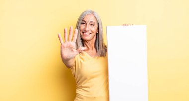 Orta yaşlı güzel bir kadın gülümsüyor ve arkadaş canlısı görünüyor, beş numarayı gösteriyor. boş tuval kavramı