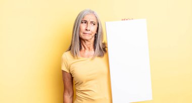 Orta yaşlı, güzel bir kadın üzgün, üzgün ya da kızgın ve yana bakıyor. boş tuval kavramı