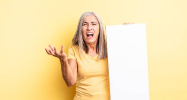 Orta yaşlı, güzel bir kadın sinirli, sinirli ve sinirli görünüyor. boş tuval kavramı