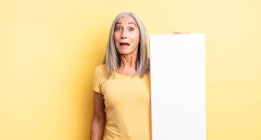 Orta yaşlı, güzel bir kadın mutlu ve hoş bir şekilde şaşırmış görünüyor. boş tuval kavramı