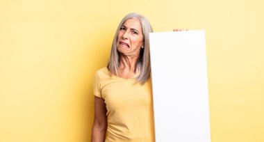 Orta yaşlı, güzel bir kadın şaşkın ve kafası karışık hissediyor. boş tuval kavramı