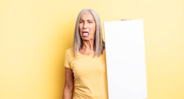 Orta yaşlı, güzel bir kadın iğreniyor, sinirleniyor ve dili dışarı çıkıyor. boş tuval kavramı