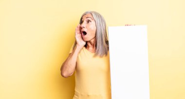 Orta yaşlı, güzel bir kadın mutlu, heyecanlı ve şaşırmış hissediyor. boş tuval kavramı