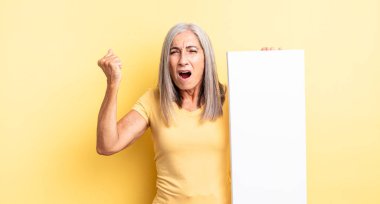 Orta yaşlı, güzel bir kadın sinirli bir ifadeyle agresif bir şekilde bağırıyor. boş tuval kavramı