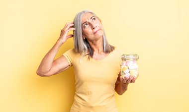 Orta yaşlı güzel bir kadın mutlu bir şekilde gülümsüyor ve hayal kuruyor ya da şüphe ediyor. Şeker şişesi konsepti