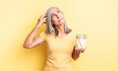 Orta yaşlı, güzel bir kadın şaşkın ve kafası karışık, kaşınıyor. Şeker şişesi konsepti