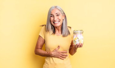 Orta yaşlı güzel bir kadın komik bir şakaya yüksek sesle gülüyor. Şeker şişesi konsepti