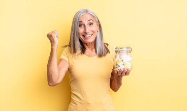 Orta yaşlı, güzel bir kadın şokta, gülüyor ve başarıyı kutluyor. Şeker şişesi konsepti