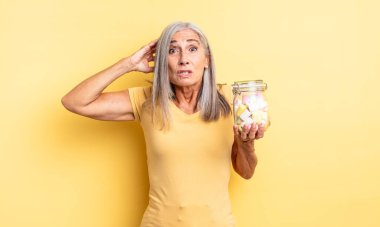 Orta yaşlı, güzel bir kadın stresli, endişeli ya da korkmuş, elleri başının üstünde. Şeker şişesi konsepti