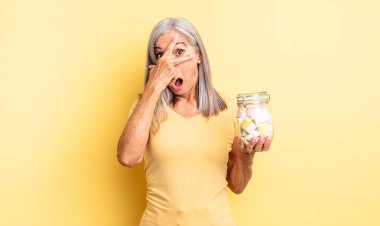 Orta yaşlı, güzel bir kadın şok olmuş, korkmuş ya da korkmuş görünüyor, yüzünü elleriyle kapatıyor. Şeker şişesi konsepti