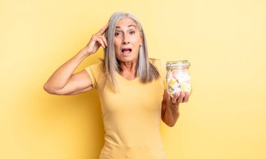 Orta yaşlı, güzel bir kadın mutlu, şaşkın ve şaşırmış görünüyor. Şeker şişesi konsepti