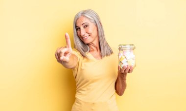 Orta yaşlı, güzel bir kadın gururla gülümsüyor ve kendinden emin bir numara oluyor. Şeker şişesi konsepti