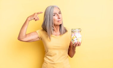 Orta yaşlı güzel bir kadın kafası karışık ve şaşkın hissediyor, deli olduğunu gösteriyor. Şeker şişesi konsepti