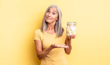 Orta yaşlı güzel bir kadın neşeli bir şekilde gülümsüyor, mutlu hissediyor ve bir konsept gösteriyor. Şeker şişesi konsepti