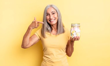 Orta yaşlı, güzel bir kadın, kendine güvenerek gülümsüyor. Şeker şişesi konsepti