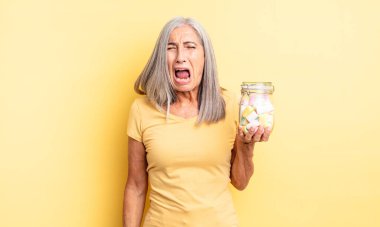 Orta yaşlı, güzel bir kadın agresif bir şekilde bağırıyor, çok kızgın görünüyor. Şeker şişesi konsepti