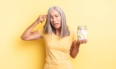Orta yaşlı, güzel bir kadın mutsuz ve stresli görünüyor, intihar jesti silah işareti yapıyor. Şeker şişesi konsepti
