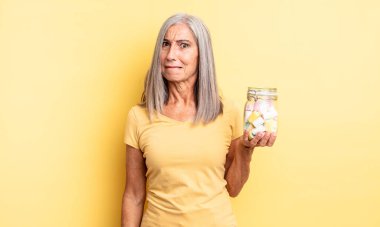 Orta yaşlı güzel bir kadın kafası karışmış ve şaşkın görünüyor. Şeker şişesi konsepti