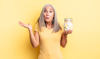 Orta yaşlı, güzel bir kadın şaşırmış ve şok olmuş görünüyor. Çenesi düşmüş ve elinde bir nesne var. Şeker şişesi konsepti