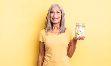 Orta yaşlı, güzel bir kadın mutlu ve hoş bir şekilde şaşırmış görünüyor. Şeker şişesi konsepti