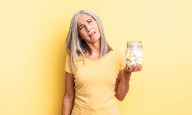 Orta yaşlı, güzel bir kadın şaşkın ve kafası karışık hissediyor. Şeker şişesi konsepti