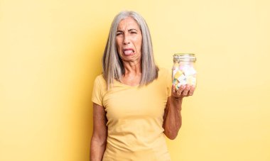 Orta yaşlı, güzel bir kadın iğreniyor, sinirleniyor ve dili dışarı çıkıyor. Şeker şişesi konsepti