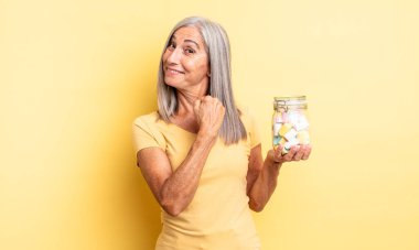 Orta yaşlı, güzel bir kadın kendini mutlu hisseder ve bir meydan okumayla yüzleşir ya da kutlama yapar. Şeker şişesi konsepti