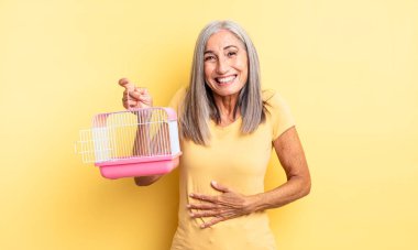 Orta yaşlı güzel bir kadın komik bir şakaya yüksek sesle gülüyor. evcil hayvan kafesi veya hapishane konsepti