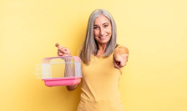 Orta yaşlı, güzel bir kadın kamerayı işaret ederek seni seçiyor. evcil hayvan kafesi veya hapishane konsepti