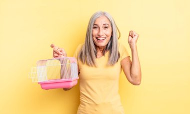 Orta yaşlı, güzel bir kadın şokta, gülüyor ve başarıyı kutluyor. evcil hayvan kafesi veya hapishane konsepti